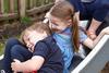 Two children piled up at the bottom of a slide and smiling