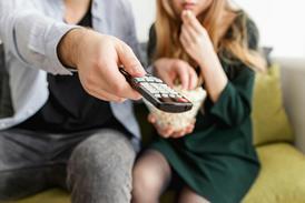 couple pointing remote control at TV screen