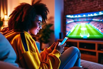 Gen Z football fan checking phone during WC match