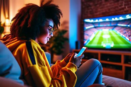 Gen Z football fan checking phone during WC match