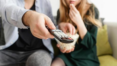 couple pointing remote control at TV screen