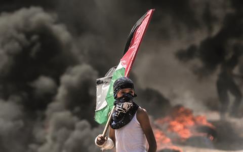 Lone youth with flag and burning bg AFP via ELVIS hi046798039